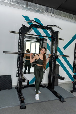 At the gym woman doing hard training exercise with barbell weights. Exercises for the buttocksの写真素材