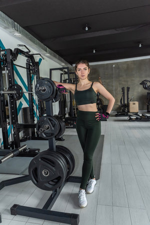 Portrait of happy fit female personal trainer while standing in gym. Are you ready to hard workout at gym centerの写真素材