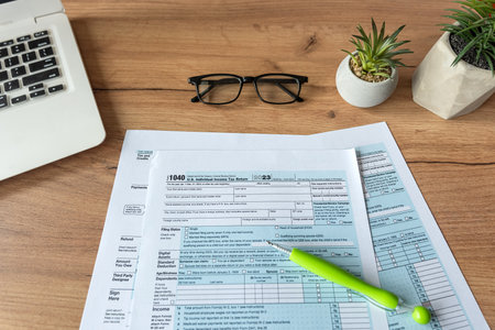1040 U.S. individual income tax form with glasses pen and online work with laptop on desk. Deadlineの写真素材