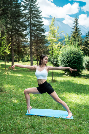 Young woman in sportswear doing streching exercise outdoors against mountain background. Healthy lifestyleの写真素材