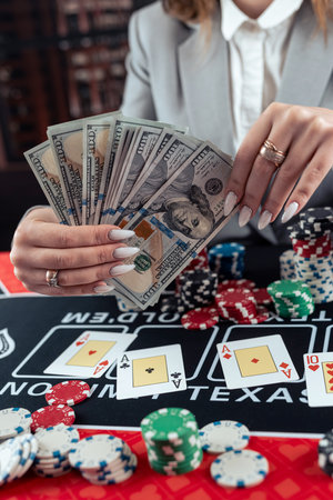Successful female player count dollar banknotes after winning poker game at casino. Gambling conceptの写真素材
