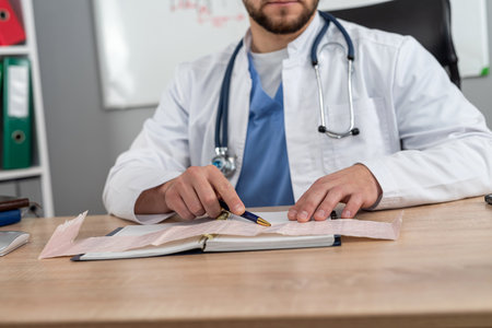 Young doctor or general practitioner sitting at workplace in hospital clinic. Writing in healthcare reportの写真素材