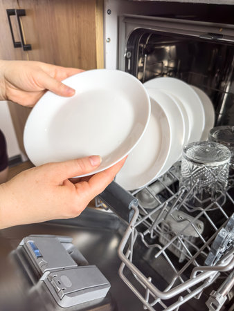 close up woman taking out clean dishes from dishwasher machine. Housewife does her houseworkの写真素材