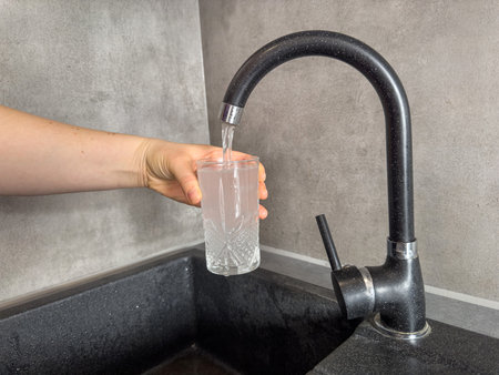 close up hand pouring fresh clean water into glass at kitchen faucet. Healthy lifestyleの写真素材