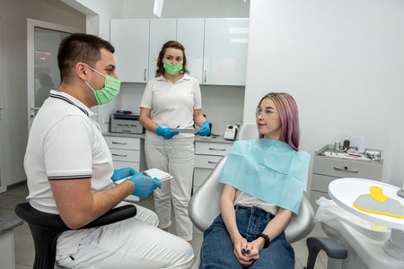 girl talking consulting with Caucasian male dentist and assistant. young woman feels happy to receive care from a professional dentist for tooth decay  gum disease in a dental care program.dentistryの写真素材