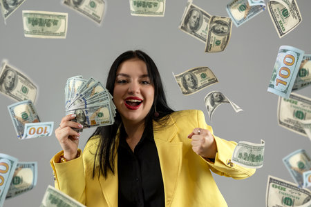 Portrait of happy woman in suit and rain of the dollar bills. Businesswoman and big money. Saving finansial conceptの写真素材