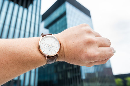 The client, hurrying to a business meeting, looks at the clock in front of the office building. Concept of timeの写真素材