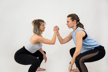 Young healthy two women doing workout pilates exercise together isolated. Teamworkの写真素材