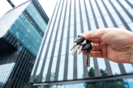 Close-up realtor broker holding a key with house against new modern building. Real estate agentの写真素材