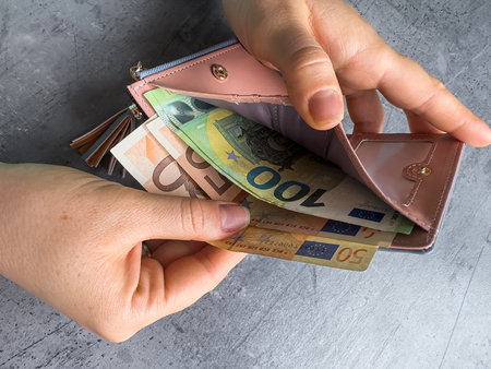 woman puts 50 100 euros in wallet or caunt money. Saving concept. Eur bills