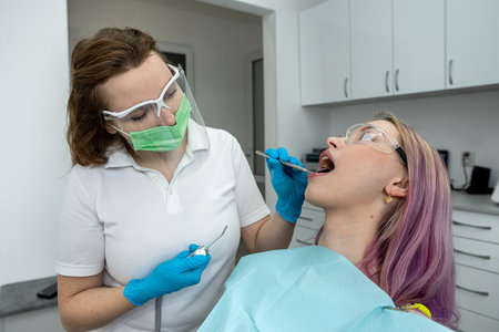 European young woman sits in a medical chair while a dentist fixes her teeth in a dental clinic. healthy oral cavity. teeth treatmentの写真素材