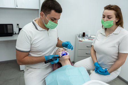 male and female dentists use a UV lamp to harden the patient's fillings. dentistry teethの写真素材