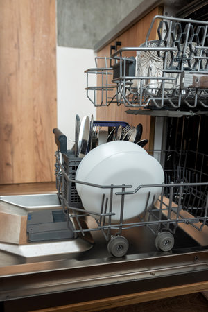 Modern open dishwasher with clean dishes after washing cycle at kitchen. Modern technologiesの写真素材