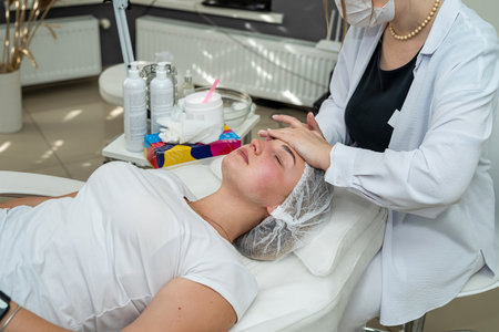beautician doing relaxing facial massage to young caucasian woman at spa salon. Concept of rejuvenation procedureの写真素材