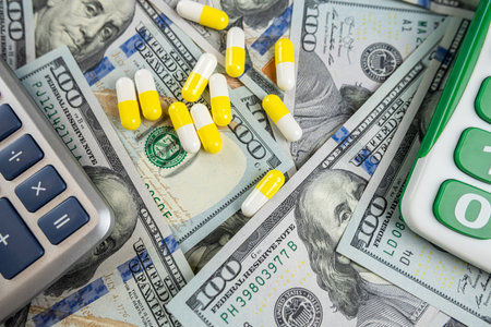 calculator with prescription pills above us american dollar money. Medical or pharmacy cost concept....
