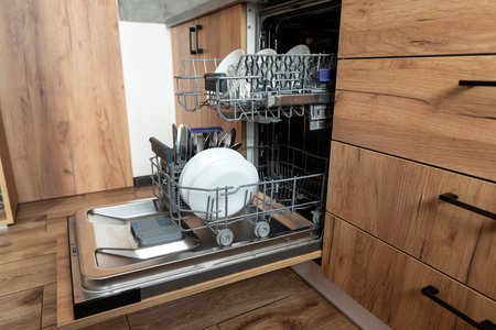 Modern kitchen with built-in open dishwasher with clean dishes