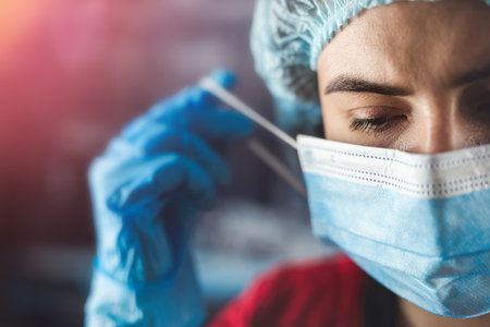 Young tired nurse or doctor taking off mask after work shift at medical clinic.