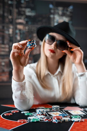 Woman posing with poker chips and playing cards in her hands at casino. Gambling conceptの写真素材