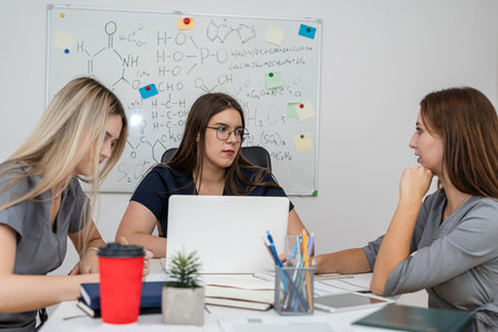 Team of woman during meeting in office, blackboard with drawn molecular structures in the backgroundの写真素材