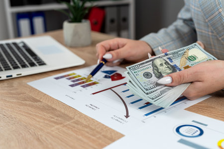close up woman holding dollars working at office with business graph and chart, investment coneptの写真素材