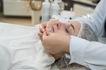 Masseur therapist doing rejuvenating facial massage procedure. Skincare by cosmetician. Dermatology conceptの写真素材