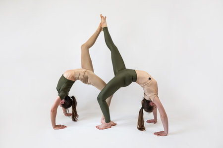 Two young fitness women in sportwear stretching practice isolated at studio. Yoga or pilates workoutの写真素材