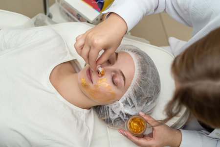Young caucasian in spa getting anti-aging cosmetic treatment with golden mask on face. Deep moisturizingの写真素材