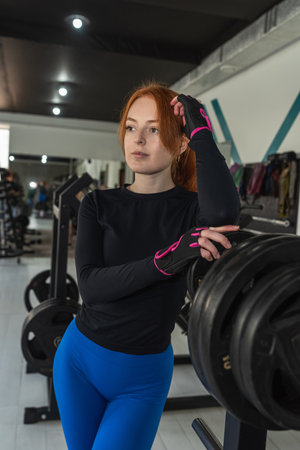 Portrait of pretty slim personal trainer standing at gym and wait here client. The concept of fitness, sport and lifestyle.の写真素材