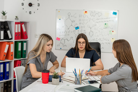 three women holding a reflection workshop in the office with chemistry formulas on whiteboardの写真素材