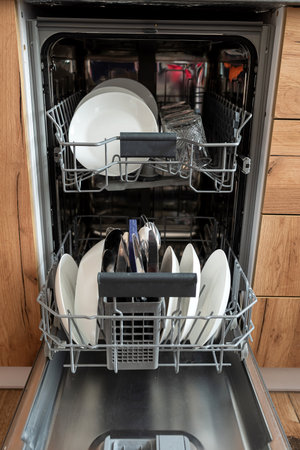Modern open dishwasher with clean dishes after washing cycle at kitchen. Modern technologiesの写真素材