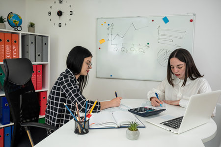 Two young business women talking and filling tax form. Time for tax. Annual reportの写真素材