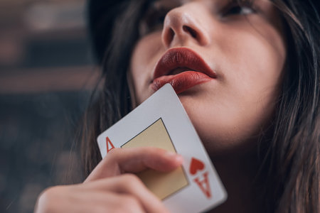 Beautiful caucasian woman showing a poker card near her red lips, closeup. Gambling concept