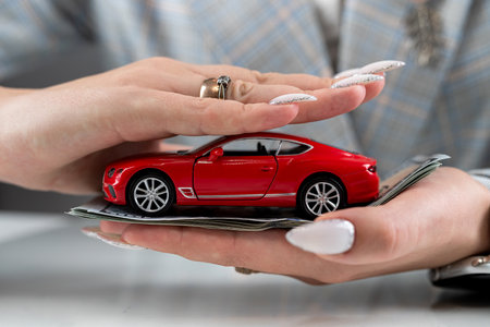 Insurance agent holding red car toy as vehicle insurance, concept of safe drivingの写真素材