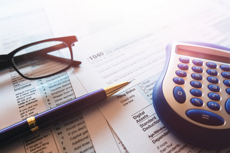 1040 US tax form with pen and calculator on office desk. Taxes burdenの写真素材
