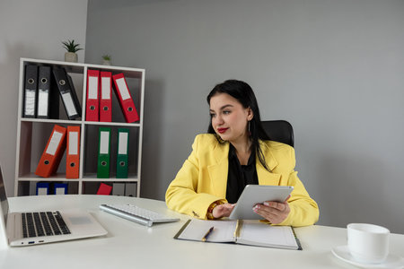 young caucasian woman writing in memo and work with laptop at home or office. Concepts of remote work, freelanceの写真素材