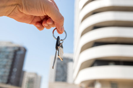 woman real estate agent holding house key on background of new buildings. Purchase conceptの写真素材