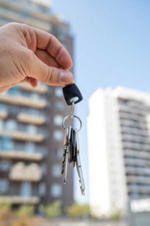 close up real estate agent holding house keys outdoor. Close-up focus on keys with cute keychain. Purchase conceptの写真素材