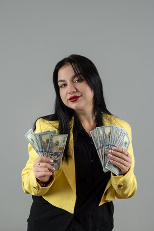 Happy business woman in yellow suit show dollar money isolated on grey. Winner expression...
