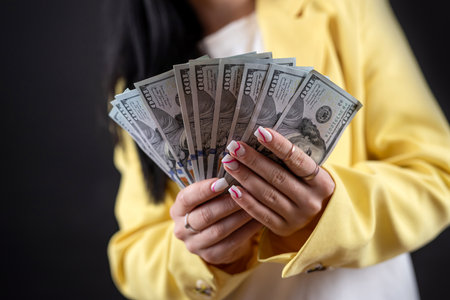 cheerful young caucasian woman hold dollar money isolated on black. Financial reward savings