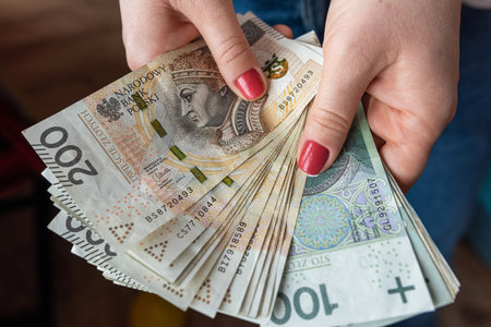 Woman holds a lot of polish money in her hands, PLN money financial concept
