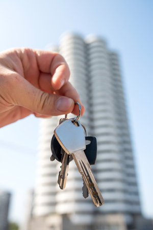 close up real estate agent holding house keys outdoor. Close-up focus on keys with cute keychain. Purchase conceptの写真素材