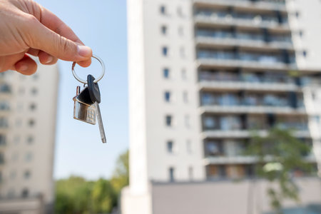 A person is standing outside a large, impressive building while holding keys, likely waiting eagerly to enter and explore the unique and intriguing interiorの写真素材