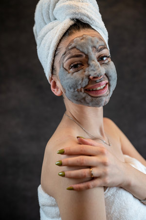 Beautiful girl applying face mask foam bubbles with charcoal isolated on black background. Skin treatmentの写真素材