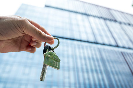 businessman holding keys for your new flat standing near the office building