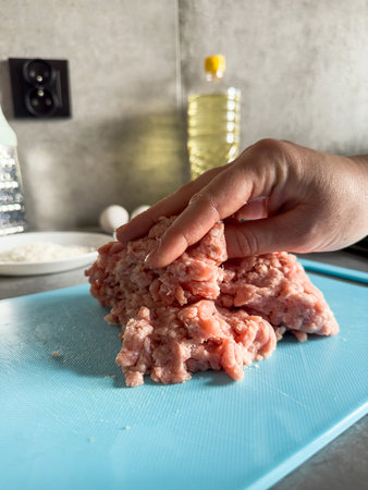 woman in the kitchen prepares delicious homemade cutlets or pelmeni from raw minced meat. Uncook raw foodの写真素材