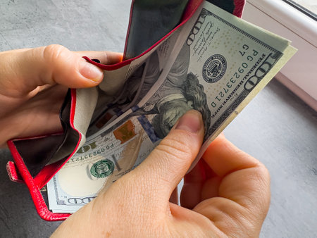 rich woman puts in a wallet 100 hundred dollar bills. Hand with money