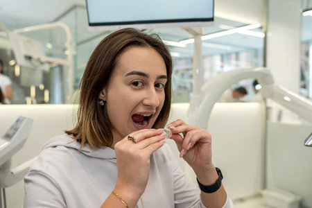 Close-up of a young Caucasian woman holding an invisible aligner that she wants to put on her teeth. Dental treatment concept.の写真素材
