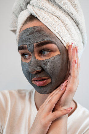 portrait of young woman getting facial care clay or mud mask isolated on white. Beauty treatmentの写真素材