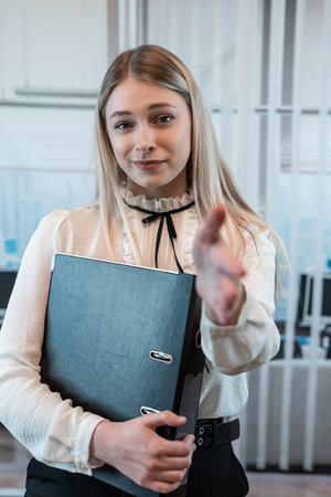 Business woman posing alone in an office and holding folders for paper documents.の写真素材