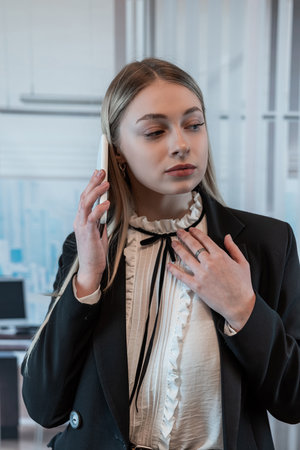 Pretty female worker stands at office and talks on the phone. Fashion portraitの写真素材